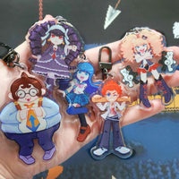 Five anime-style acrylic keychains held in a hand, featuring characters in purple, blue, orange, and brown outfits with key rings and clips.