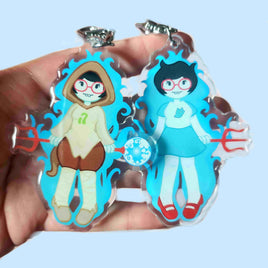 Two cartoon character pendants held in a hand against a light blue background