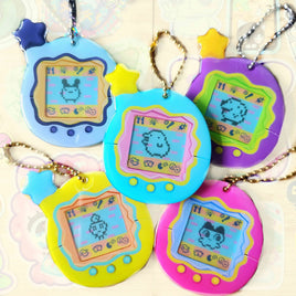 Five colorful  game-based keychains arranged together on a light patterned background. The toys come in pastel blue, turquoise, purple, yellow, and pink, each with a star-shaped antenna and ball chain.