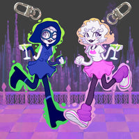 Two cartoon-style acrylic keychain charms with metal swivel clips, shown against a dark illustrated cityscape background. The left charm depicts a blue-haired character in a blue dress with green slime accents and a martini glass.