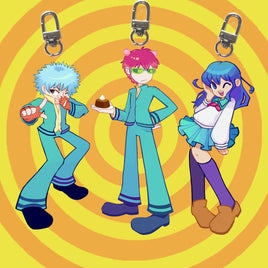 Three anime-style keychain charms with metal lobster clasps hang against a yellow and orange spiral background. The characters wear matching teal outfits and have blue, pink, and purple hair, with one holding a small cake.